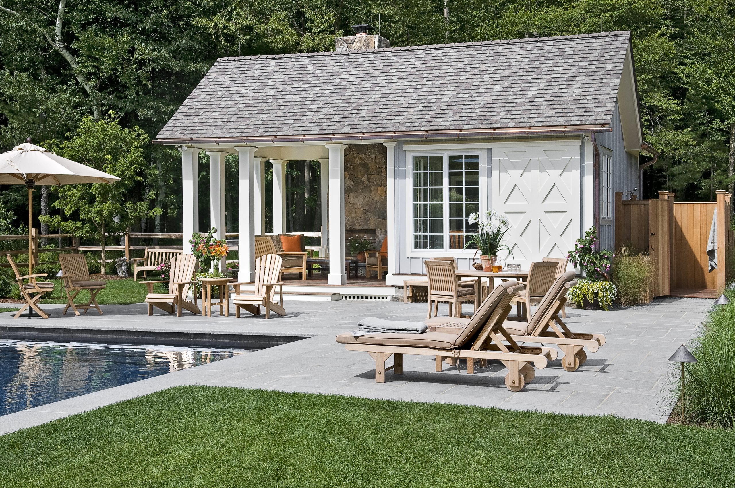 Home Shingled pool house with a columned terrace and teak furniture